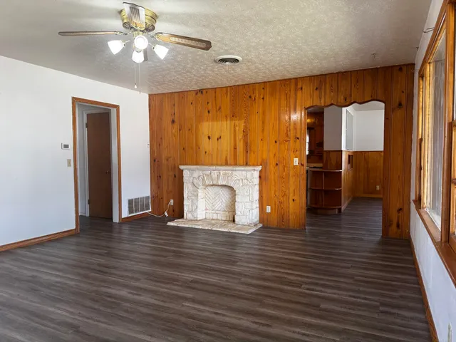 an empty room with wooden floor fireplace and windows