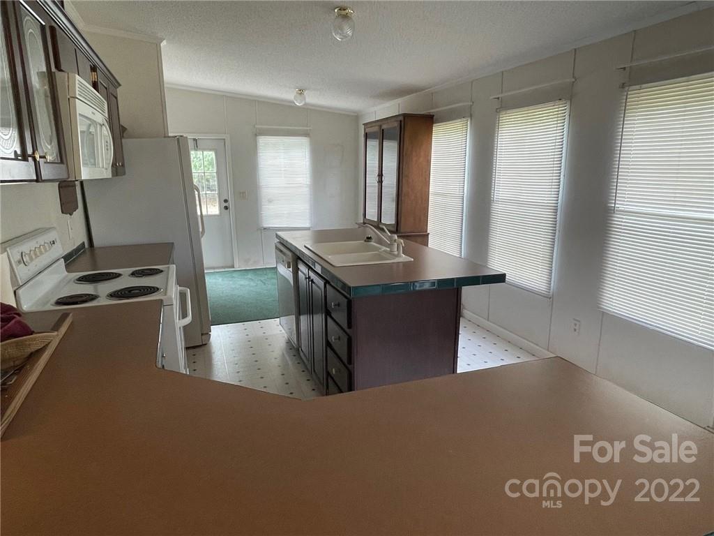 97 County Rd S-13-678 Jefferson, SC 29718 - Photo 12 of 24 a kitchen with kitchen island granite countertop a stove and a refrigerator