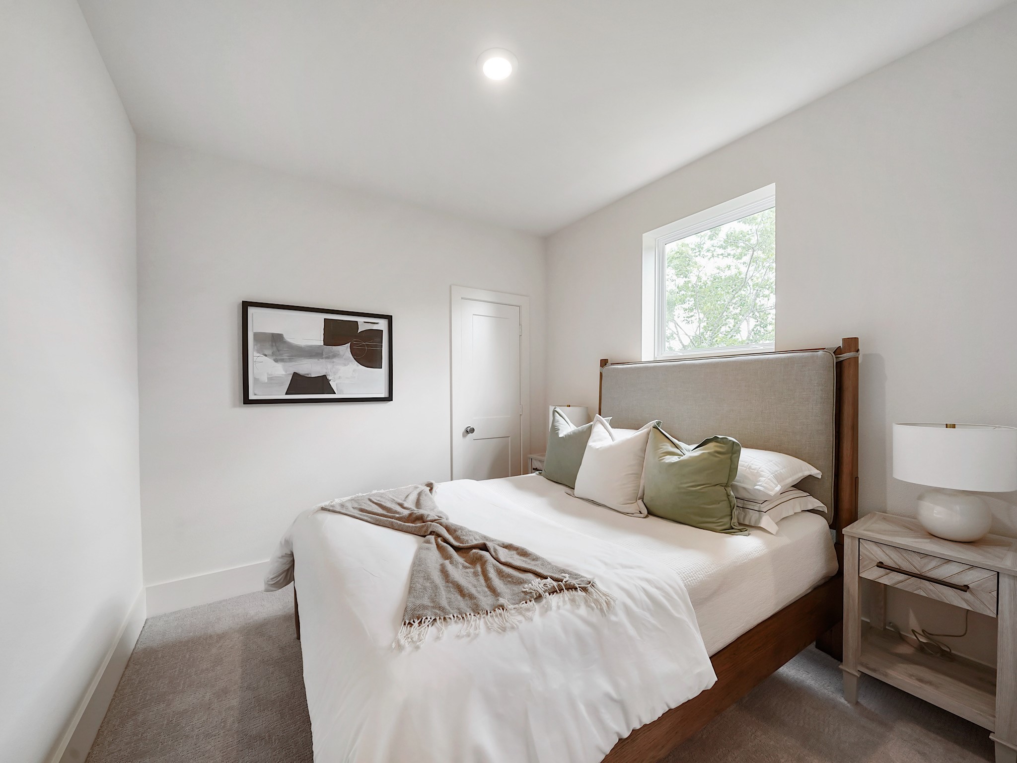 861 Rachel Street, Unit E Houston, TX 77091 - Photo 19 of 29 This inviting second bedroom offers a serene retreat with its soft, neutral palette, cozy bedding, and ample natural light, perfect for relaxation or guests.