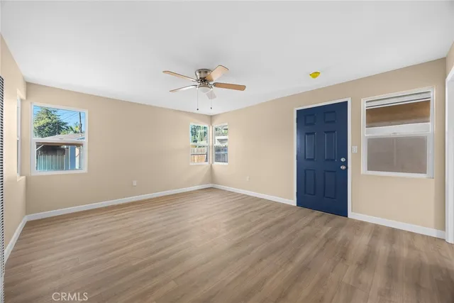 a view of an empty room with a window and wooden floor
