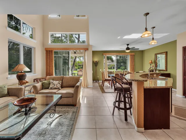 a living room with furniture potted plant and kitchen view
