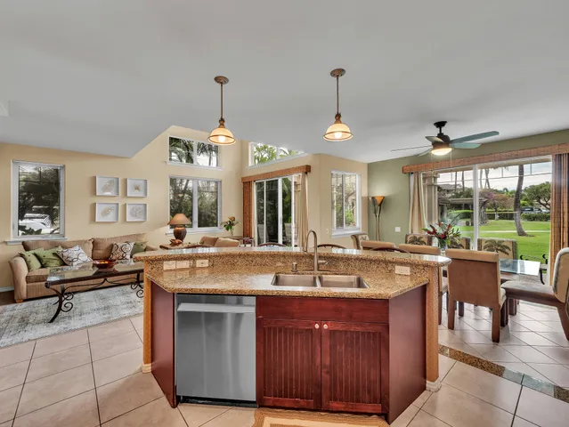 a kitchen with a stove a sink and a living room view
