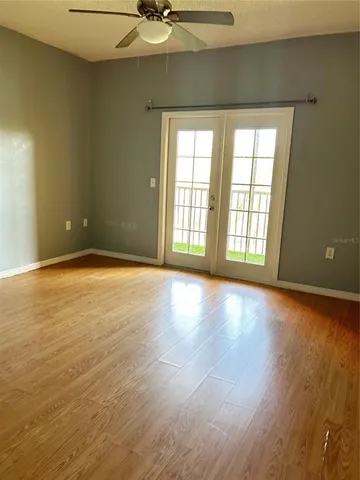 a view of an empty room with a window and wooden floor