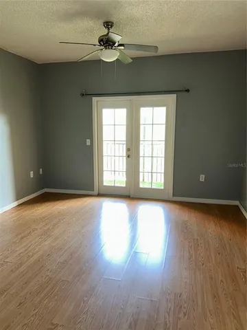 a view of an empty room with wooden floor and a window