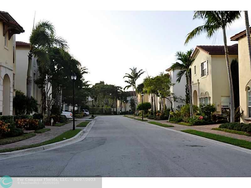 105 Via Floresta Drive Boca Raton, FL 33487 - Photo 22 of 26 a row of palm trees and a yard in front of the house