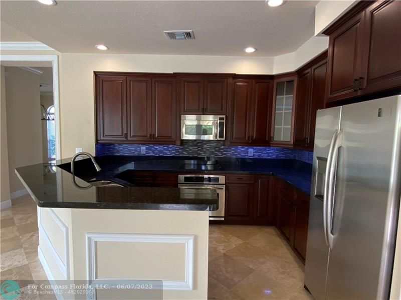 105 Via Floresta Drive Boca Raton, FL 33487 - Photo 8 of 26 a kitchen with granite countertop a refrigerator a stove a sink and cabinets