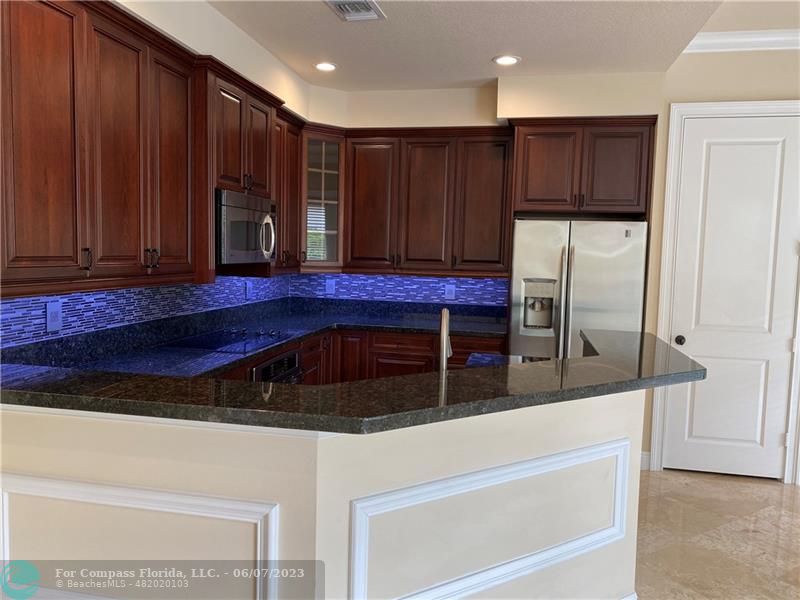 105 Via Floresta Drive Boca Raton, FL 33487 - Photo 9 of 26 a kitchen with stainless steel appliances granite countertop wooden cabinets a refrigerator and a sink