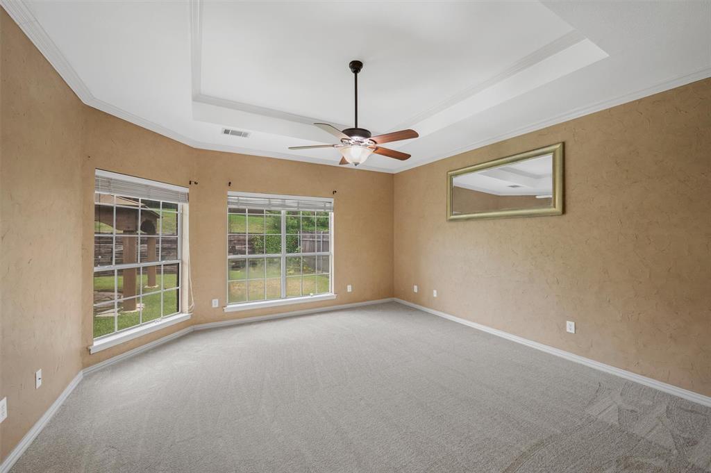 5607 Ranger Drive Rockwall, TX 75032 - Photo 20 of 40 Spacious room featuring a tray ceiling with crown molding, a ceiling fan, and light-colored carpeting