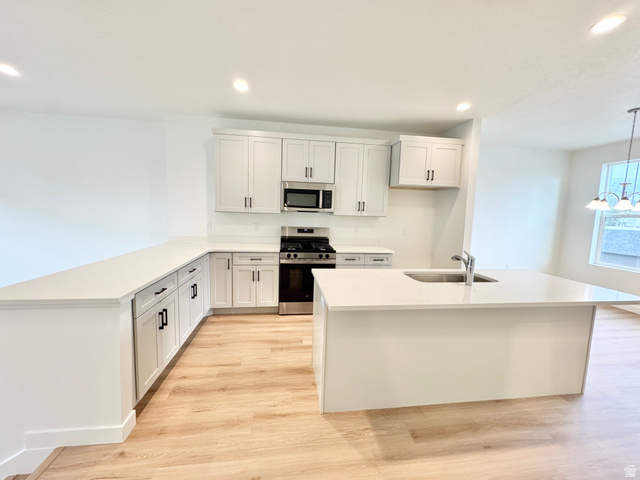 1650 North Main Street Layton, UT 84041 - Photo 7 of 24 Modern kitchen featuring light wood-finish flooring, white cabinetry with black hardware, white countertops, and stainless steel appliances
