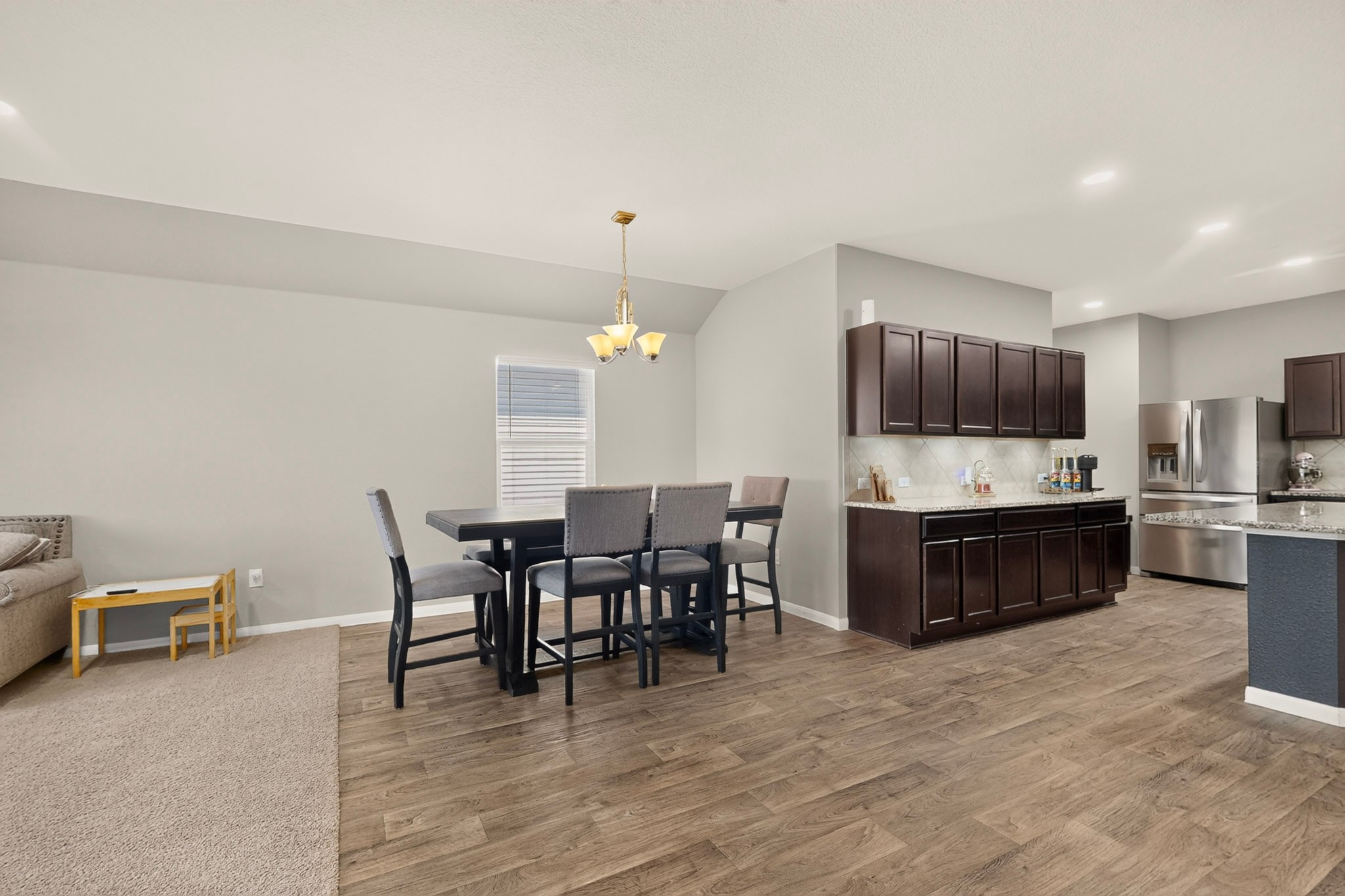 11612 Andesite Road Manor, TX 78653 - Photo 15 of 40 Rich wood-look flooring connects a comfortable dining space to the open-concept kitchen.