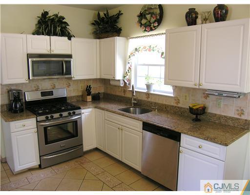 46 Lexington Road Monmouth Junction, NJ 08852 - Photo 5 of 10 a kitchen with stainless steel appliances granite countertop a sink a stove a microwave and wooden cabinets