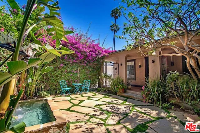 a view of a house with a tree and flower plants