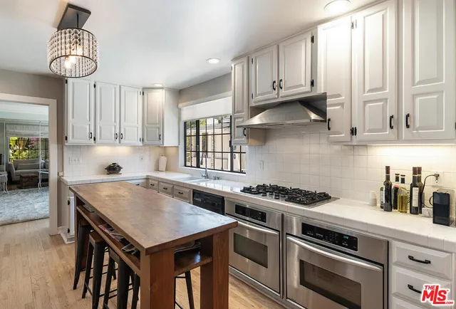 a kitchen with stainless steel appliances granite countertop a stove a sink dishwasher and cabinets with wooden floor