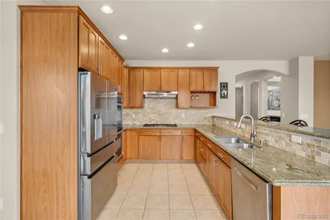 a large kitchen with stainless steel appliances granite countertop a sink and a refrigerator