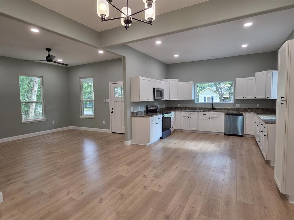 1745 East Cherry Street Paris, TX 75460 - Photo 6 of 40 a large kitchen with cabinets wooden floor and stainless steel appliances