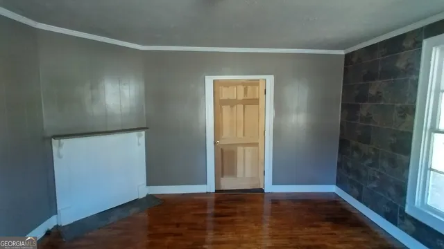 a view of an empty room with wooden floor and closet