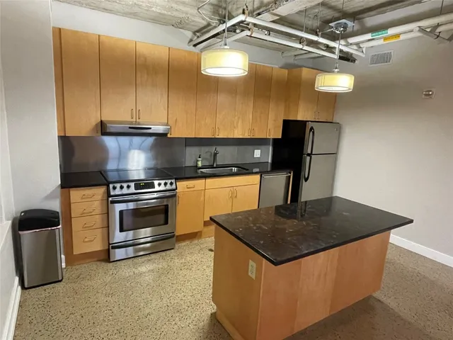 a kitchen with granite countertop stainless steel appliances a sink and a stove