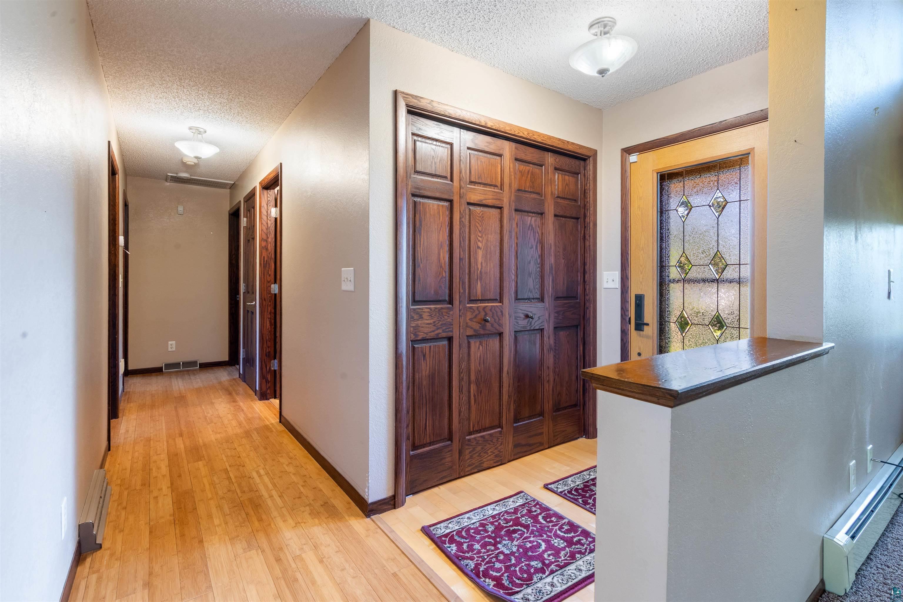 44 Highgate Street Superior, WI 54880 - Photo 4 of 47 Entryway featuring a decorative glass front door, bi-fold closet doors, and wood-finish flooring extending into a hallway