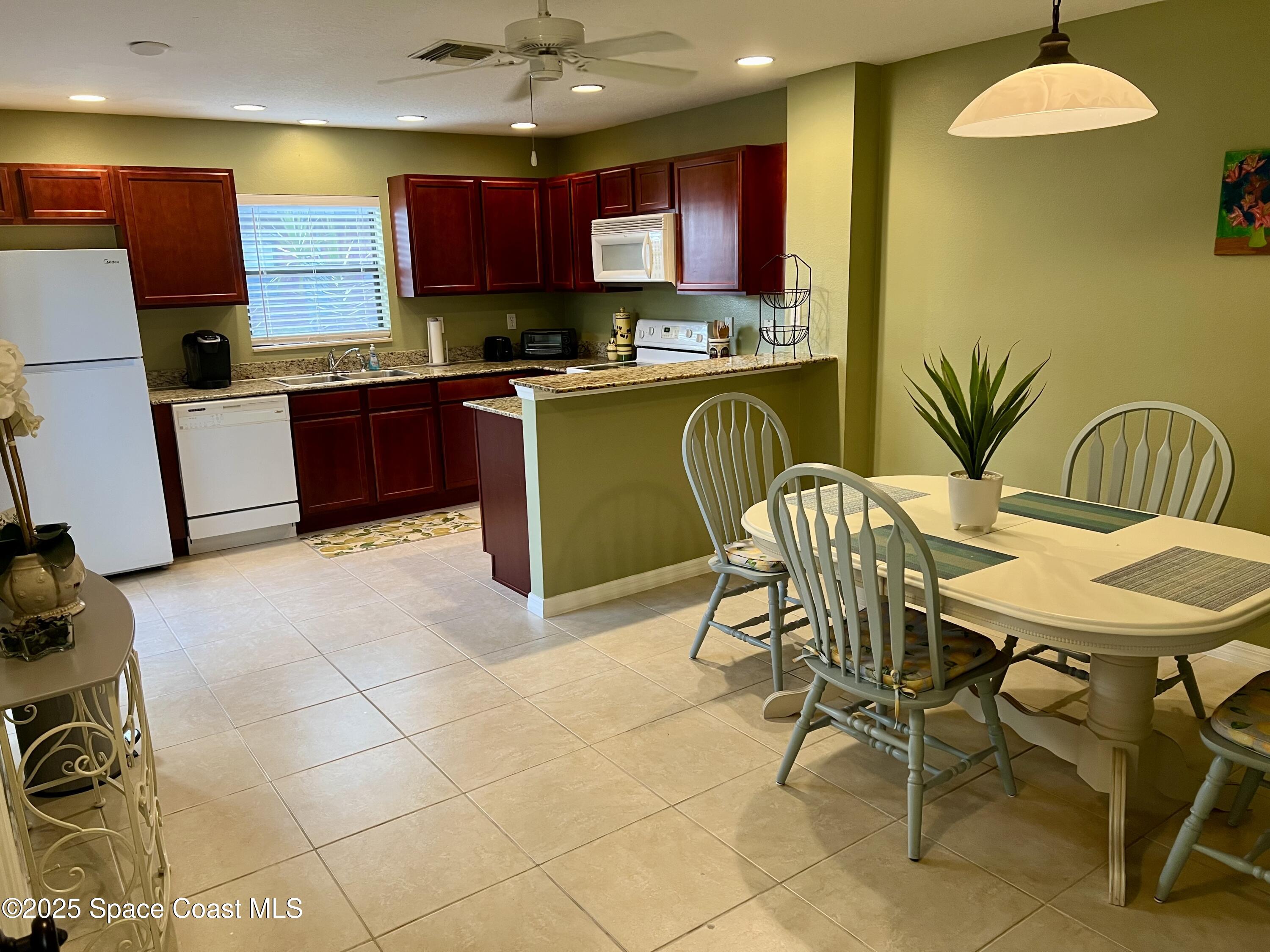 56 Piney Branch Way, Unit A Melbourne, FL 32904 - Photo 4 of 17 a kitchen with stainless steel appliances granite countertop a table chairs sink and cabinets