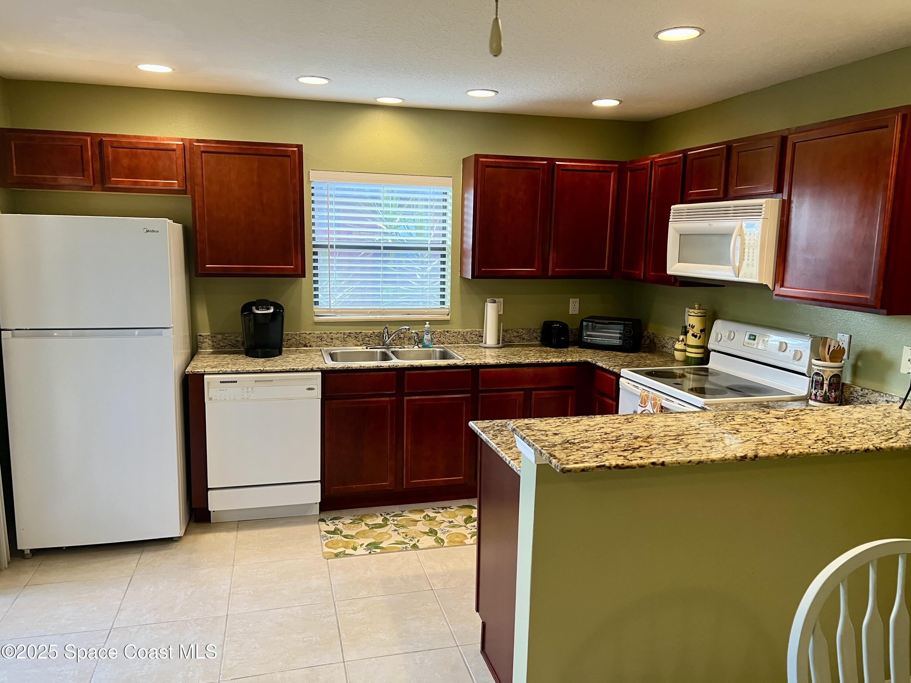 56 Piney Branch Way, Unit A Melbourne, FL 32904 - Photo 6 of 17 a kitchen with stainless steel appliances granite countertop a refrigerator sink stove and microwave