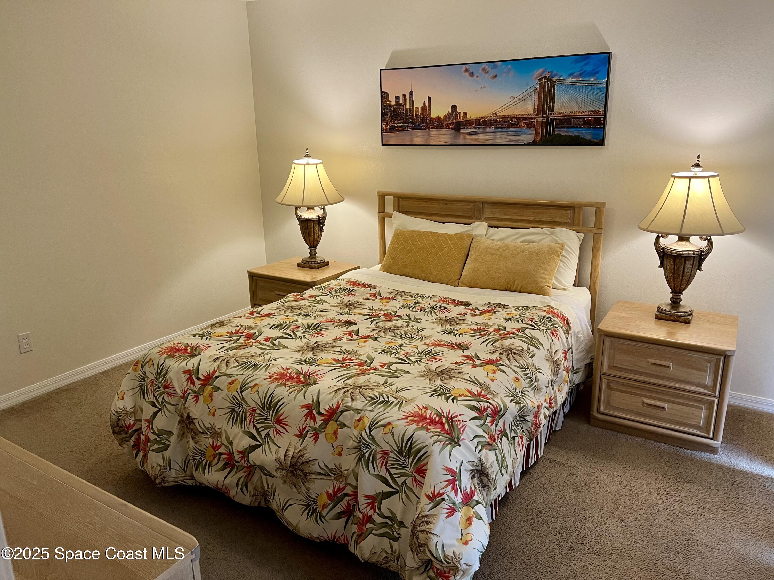 56 Piney Branch Way, Unit A Melbourne, FL 32904 - Photo 10 of 17 a bed sitting in a bedroom next to a lamp with a chandelier