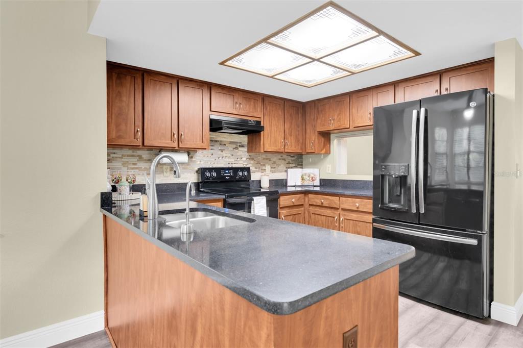 7230 Hummingbird Lane New Port Richey, FL 34655 - Photo 11 of 41 a kitchen with stainless steel appliances granite countertop a refrigerator a sink a stove a microwave and island