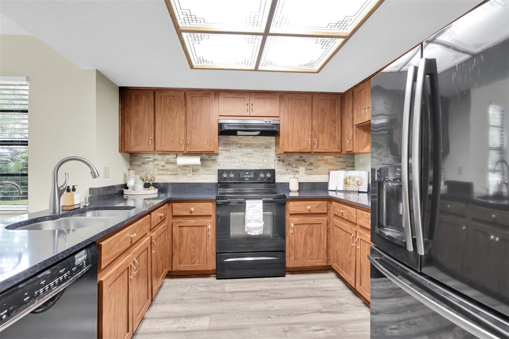 7230 Hummingbird Lane New Port Richey, FL 34655 - Photo 12 of 41 a kitchen with stainless steel appliances granite countertop a stove a sink dishwasher and a refrigerator