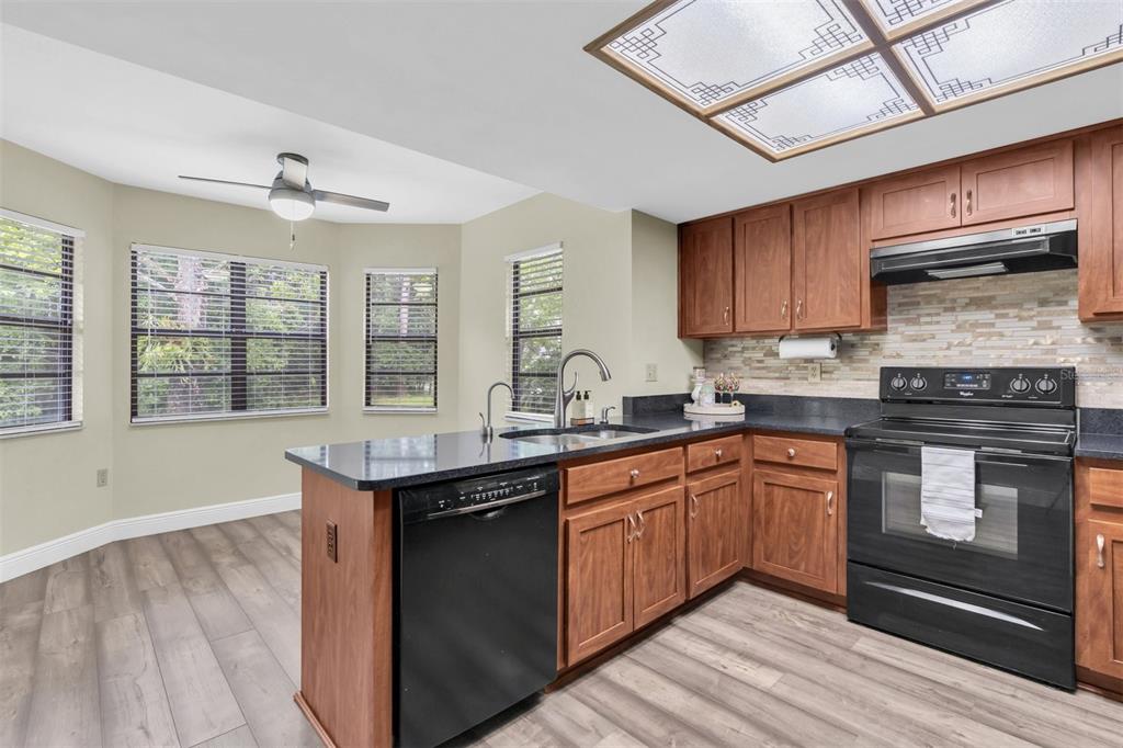7230 Hummingbird Lane New Port Richey, FL 34655 - Photo 13 of 41 a kitchen with stainless steel appliances granite countertop a stove a sink dishwasher and a microwave oven with cabinets
