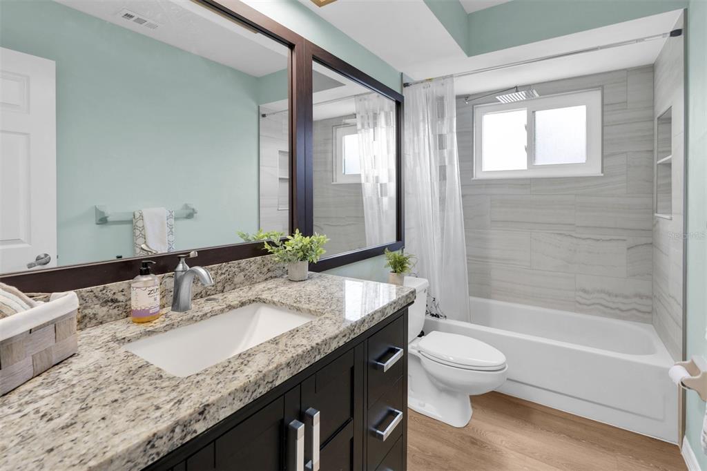 7230 Hummingbird Lane New Port Richey, FL 34655 - Photo 24 of 41 a bathroom with a granite countertop bathtub sink vanity mirror and toilet