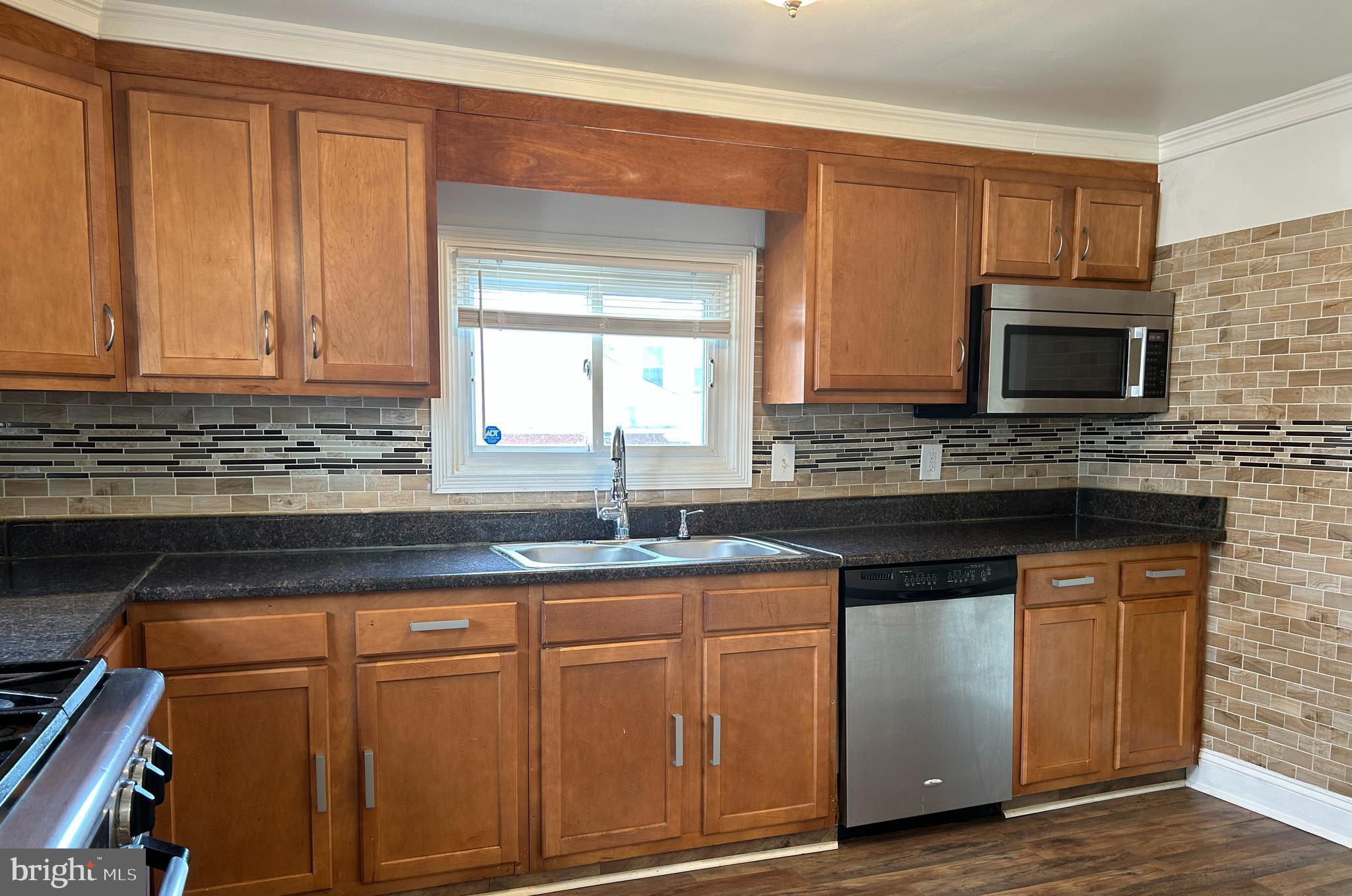 3405 Dennlyn Road Baltimore, MD 21215 - Photo 5 of 20 a kitchen with granite countertop cabinets stainless steel appliances a sink and wooden floor