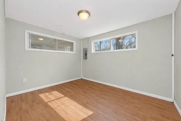 a view of an empty room with wooden floor and a window