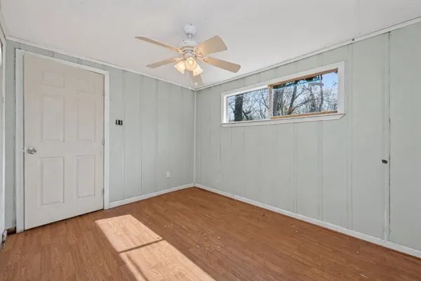 a view of an empty room with wooden floor and a window