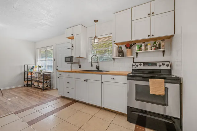 a kitchen with stainless steel appliances a stove a sink and white cabinets