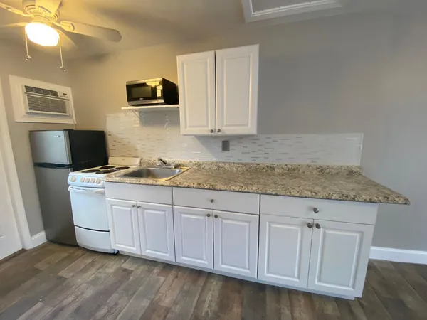 a kitchen with granite countertop a sink cabinets and wooden floor