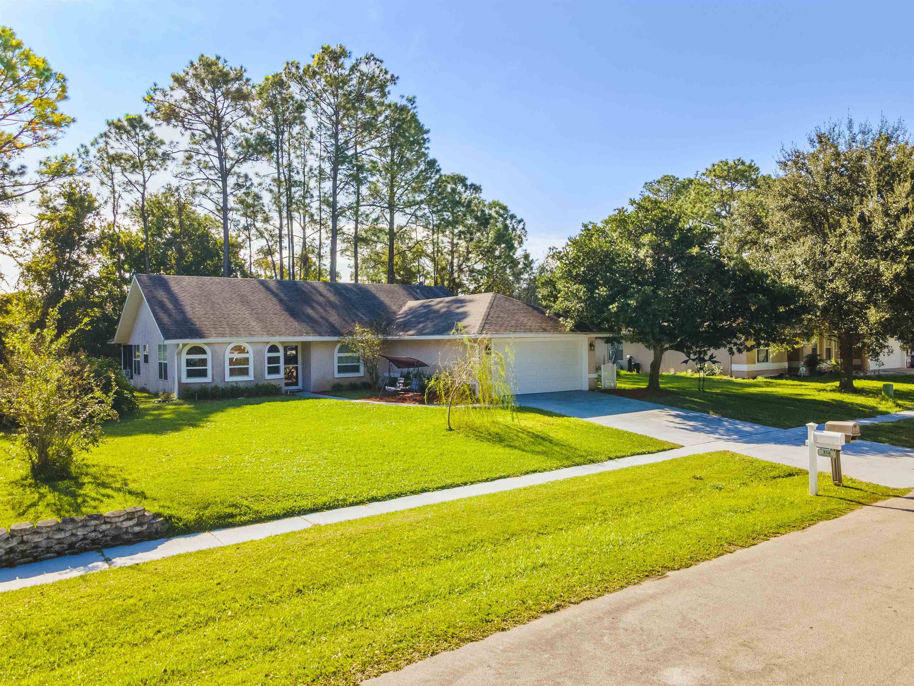 Ranch-style home with concrete driveway, a front lawn, and an attached garage