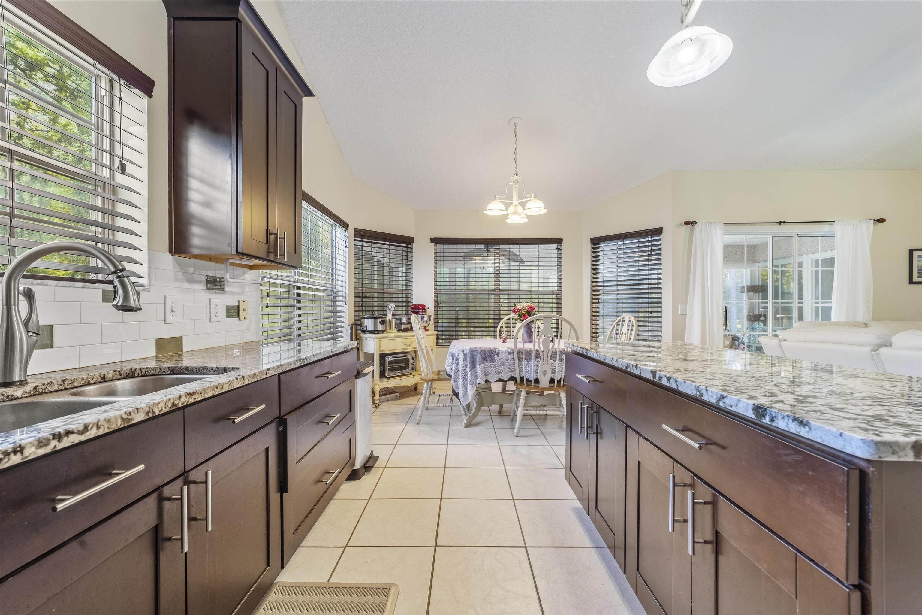 311 Graciela Circle St. Augustine, FL 32086 - Photo 12 of 65 Kitchen featuring dark brown cabinets, pendant lighting, light stone counters, light tile patterned floors, and a chandelier