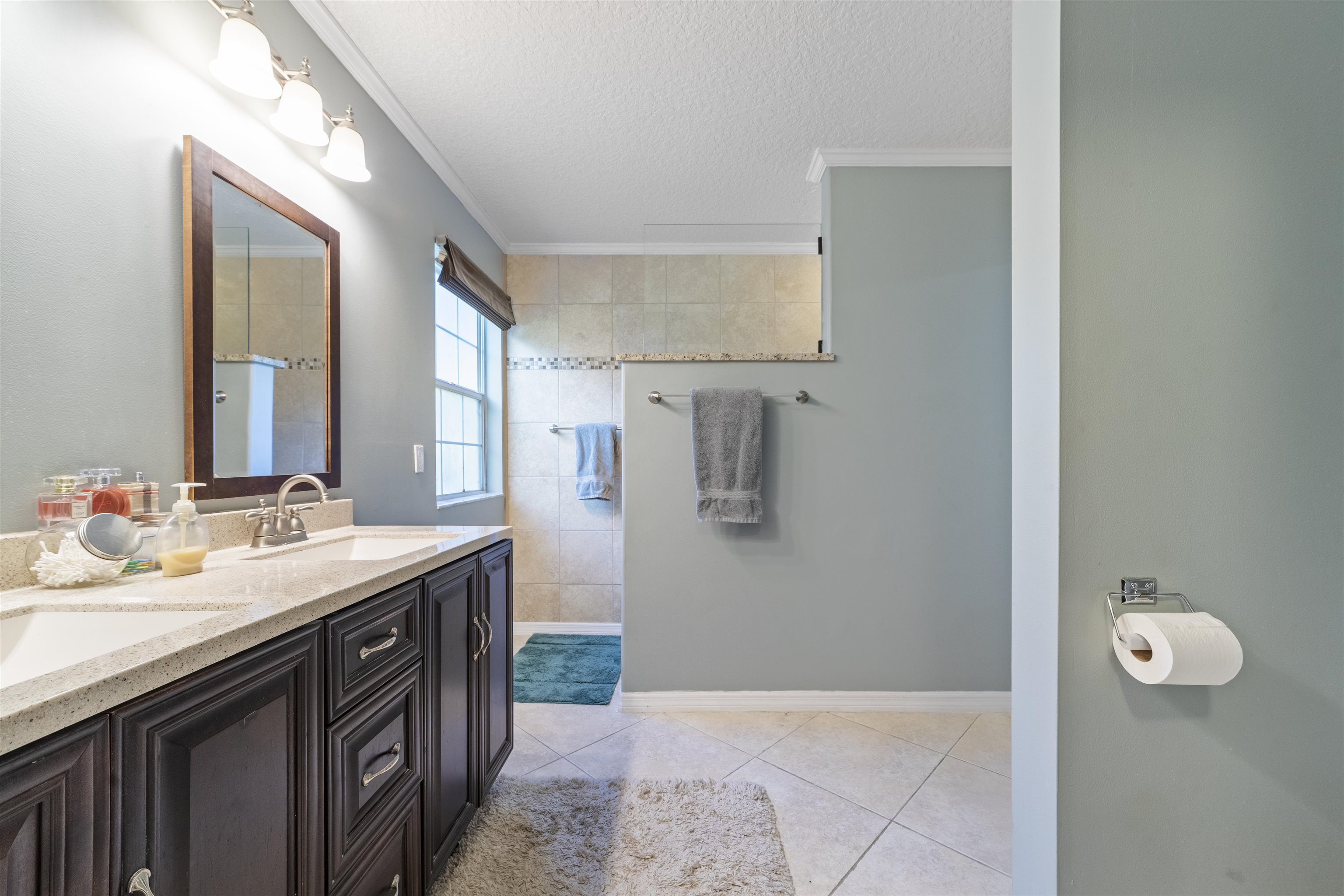 311 Graciela Circle St. Augustine, FL 32086 - Photo 39 of 65 Full bathroom featuring a textured ceiling, double vanity, light tile patterned floors, ornamental molding, and a walk in shower