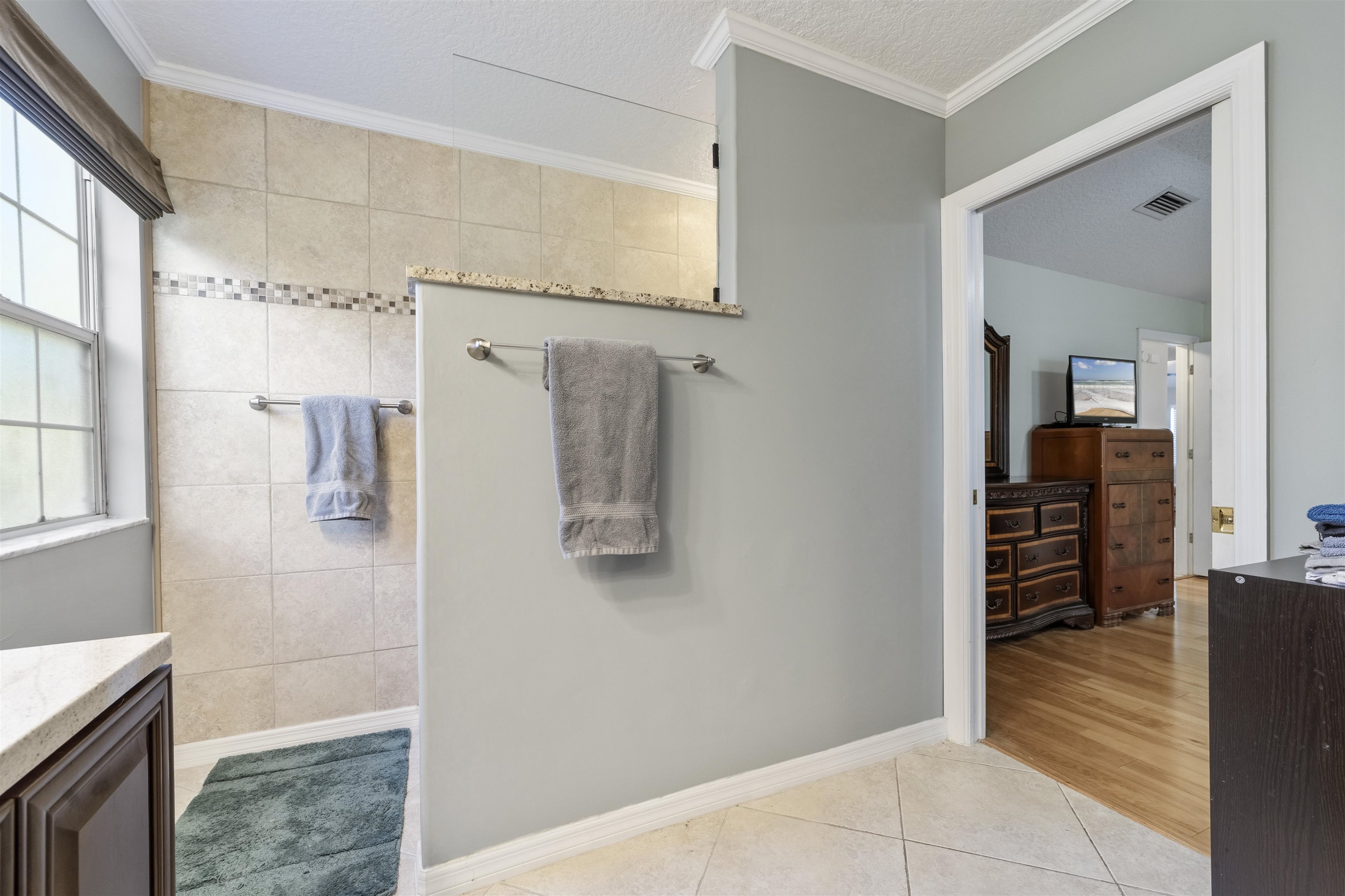 311 Graciela Circle St. Augustine, FL 32086 - Photo 40 of 65 Bathroom featuring crown molding, light tile patterned floors, vanity, a walk in shower, and a textured ceiling