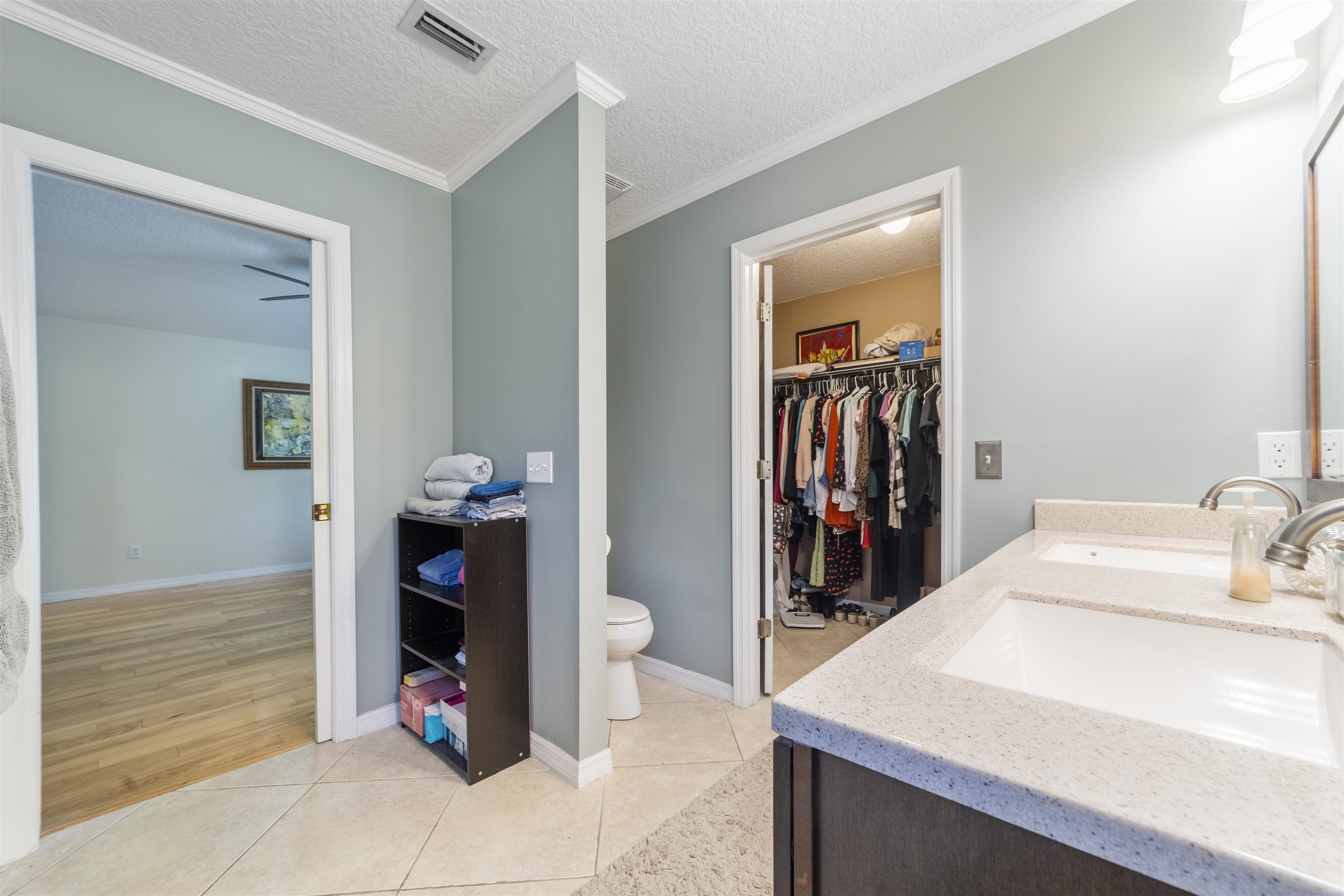 311 Graciela Circle St. Augustine, FL 32086 - Photo 43 of 65 Bathroom featuring a spacious closet, a textured ceiling, light tile patterned flooring, double vanity, and crown molding