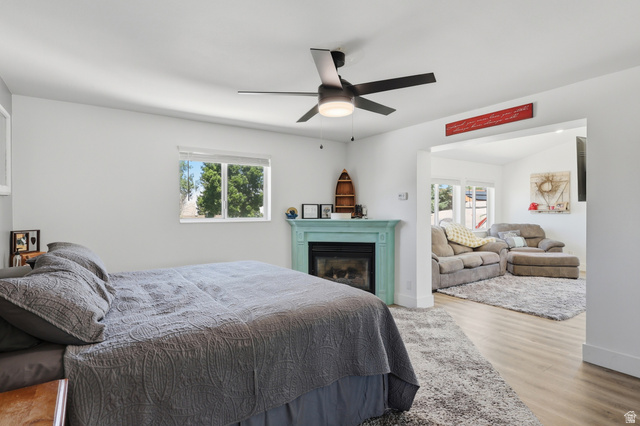 114 North Clark Lane Elk Ridge, UT 84651 - Photo 7 of 26 Bedroom featuring a decorative fireplace with a light blue mantel, a ceiling fan with integrated lighting, and a window providing natural light