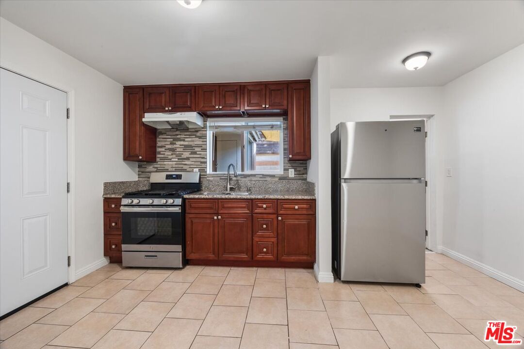 2840 South Mansfield Avenue Los Angeles, CA 90016 - Photo 42 of 50 a kitchen with stainless steel appliances granite countertop a refrigerator and a stove