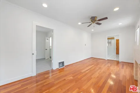 a view of empty room with wooden floor and fan