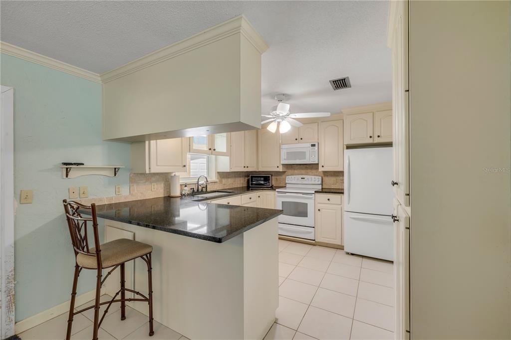 2416 Pine Tree Drive Edgewater, FL 32141 - Photo 22 of 50 a kitchen with cabinets and chairs