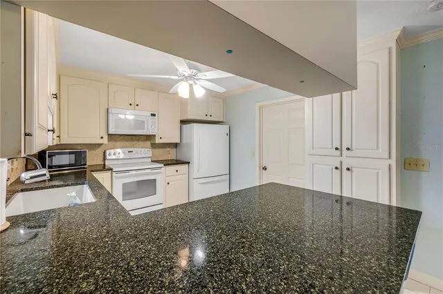 a kitchen with granite countertop white cabinets white appliances with a sink and dishwasher