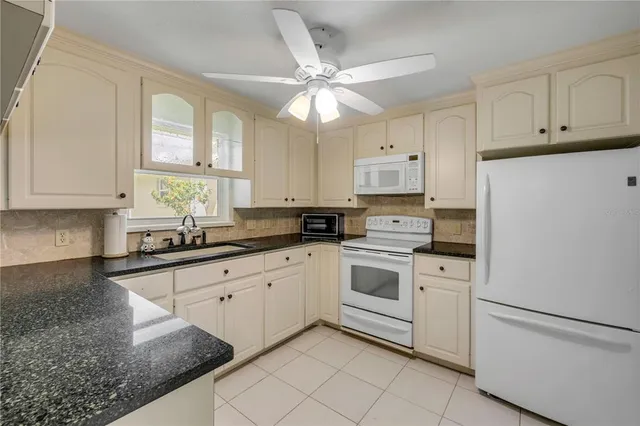 a kitchen with granite countertop white cabinets white stainless steel appliances with a sink and dishwasher