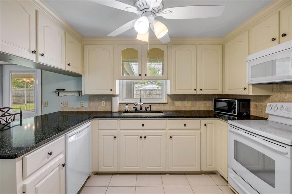 2416 Pine Tree Drive Edgewater, FL 32141 - Photo 26 of 50 a kitchen with granite countertop white cabinets white stainless steel appliances with a sink and dishwasher