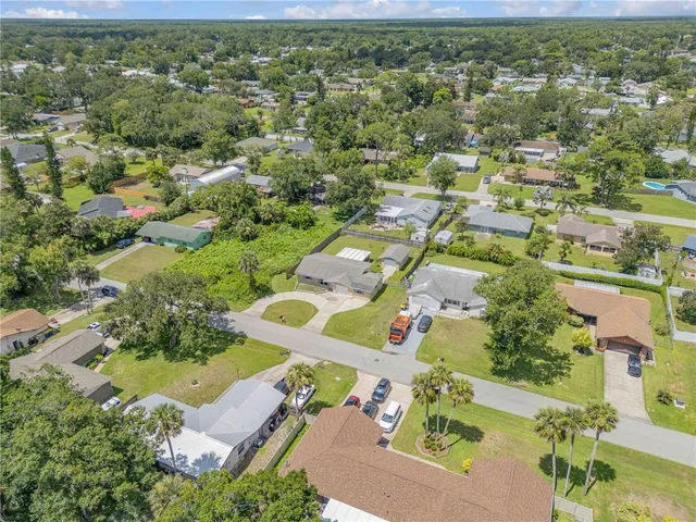 an aerial view of residential houses with outdoor space and trees