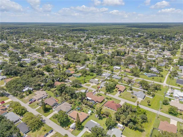 an aerial view of residential houses with outdoor space and trees