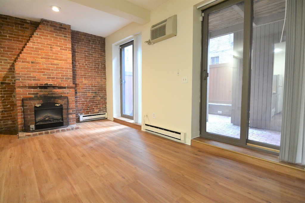 67 St Germain Street, Unit 191 Boston, MA 02115 - Photo 2 of 13 an empty room with wooden floor fireplace and windows
