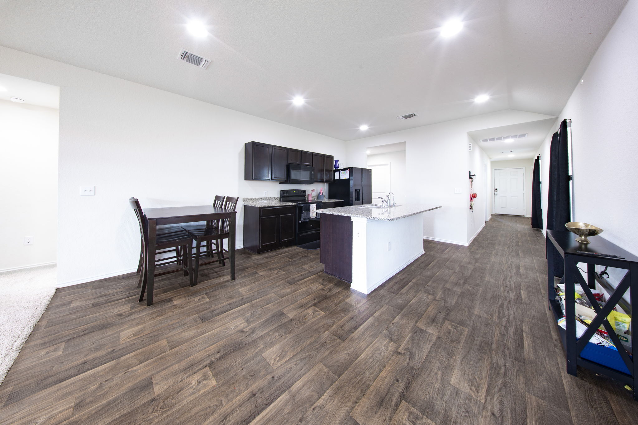 14903 Tuff Road Manor, TX 78653 - Photo 4 of 25 Functional kitchen with ample counter space and an inviting eat-in island, perfectly complemented by rich flooring.